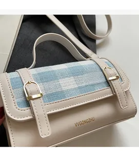 Close-up of contrast woven plaid flap and gold metal buckles on a small crossbody bag
