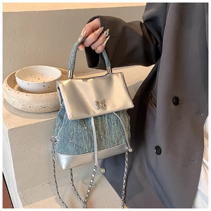 Détail du sac à dos en denim bleu avec cuir argenté et boucle papillon en cristal