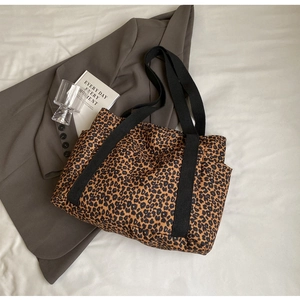 Detalle de bolso tote de lona con estampado de leopardo, asa negra y bolsillo lateral