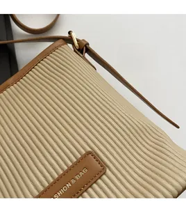 Detailed macro view of beige pleated fabric with brown leather trim and metal hardware
