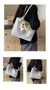 Detailed macro view of the glossy patent leather material and cute bear charm on blue tote bag