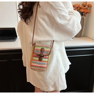 Detailed side view of rainbow woven straw mini crossbody bag with leather strap and toggle