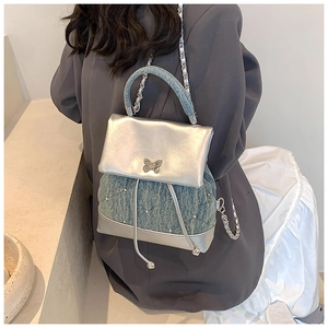 Détail du mini sac à dos en jean bleu et argent avec fermoir papillon et bandoulière chaîne