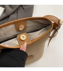 Detail of khaki pleated bucket bag with magnetic closure and premium hardware finish