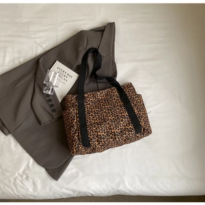 Detalle macro del bolso tote de lona leopardo con bolsillos laterales y correa negra