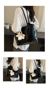 Detail of black faux leather tote bag with a plush bear charm for daily commuting