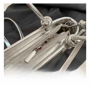 Close-up of sleek silver bucket bag with high-quality metal zipper and knot handle detail