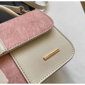 Dettaglio ravvicinato della borsa a contrasto rosa e beige con chiusura dorata