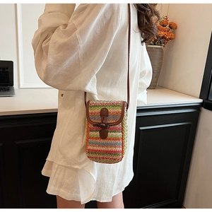 Close-up of rainbow woven straw phone bag with brown leather flap and stylish crossbody strap