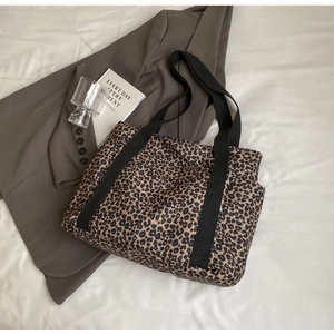 Detalle de bolso tote de lona con estampado de leopardo y asas de tejido en negro