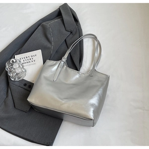 Detailed close-up of large silver metallic tote bag with high-shine texture and handles