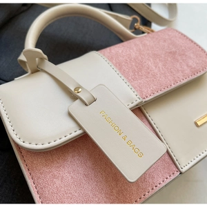 Dettaglio della mini borsa bicolore con cuciture rifinite e targhetta con logo
