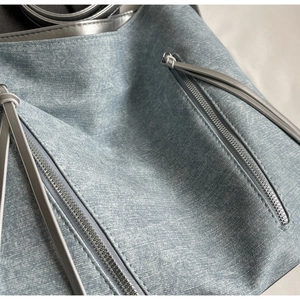 Detail of light blue denim texture fabric with silver metal zippers and long pull cords
