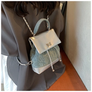 Détail du mini sac à dos en denim et argent avec texture matelassée et fermoir papillon