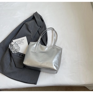 Detailed top view of large silver metallic tote bag with thin straps on neutral background