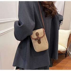 Close-up of straw mini phone bag with leather trim and retro horn buckle closure