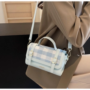 Detail of light blue and white checkered crossbody bag with gold buckles and logo