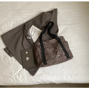 Bolso tote de lona con estampado de leopardo junto a una chaqueta y una tablet