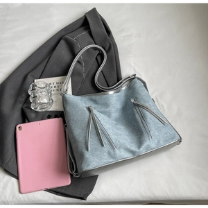 Detail of light blue denim texture tote bag with silver trim and long fringe tassels