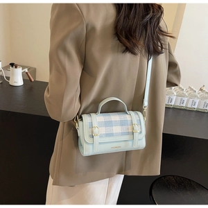 Detail of light blue checkered crossbody bag with adjustable strap and metal buckle