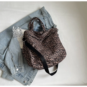 Dettaglio della borsa tote leopardata con tracolla nera e accessori di stile