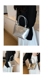 Detail of silver metallic wrinkled texture bucket bag with dual handles and slim strap