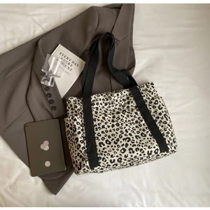 Detalle del bolso tote de lona con estampado de leopardo, bolsillo lateral y asas negras