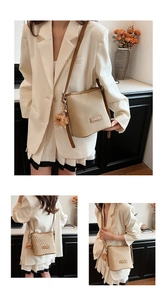 Detail of beige pleated bucket bag featuring a brown shoulder strap and a cute bear charm
