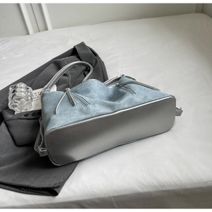 Close-up of light blue denim tote with silver metallic leather details and drawstring