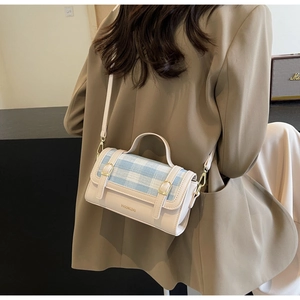 Close-up of contrast checkered small square bag featuring gold hardware and top handle