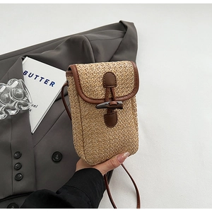 Macro detail of straw woven mini bag featuring leather trim and a dark horn button closure