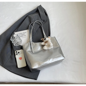 Silver metallic tote bag with plush bear charm styled with aesthetic fashion accessories