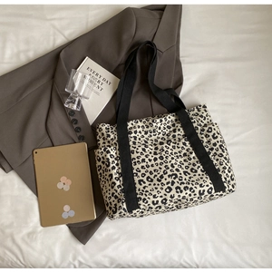 Detalle de bolso tote de lona de leopardo con bolsillo lateral y correa ancha negra