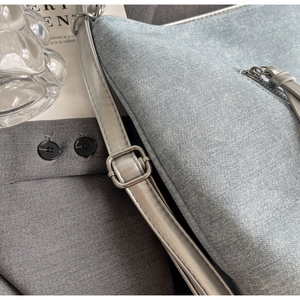 Detail of blue denim textured shoulder bag with silver hardware and leather tassel