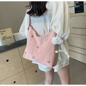 Dettaglio borsa hobo rosa con ciondoli a farfalla in argento e pendente a nuvola morbida
