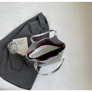 Detail of silver tote bag featuring burgundy lining and a white removable zipper pouch