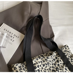 Primer plano de bolso tote de lona con estampado de leopardo y asas negras anchas