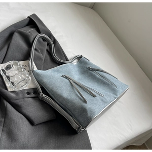 Detail of light blue denim texture shoulder bag with silver grey leather straps and zippers