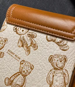 Dettaglio di una borsa a tracolla in pelle beige con stampa di orsetto marrone e cuciture