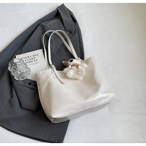 Detail of minimalist cream tote bag with cute white plush bear pendant on smooth PU leather