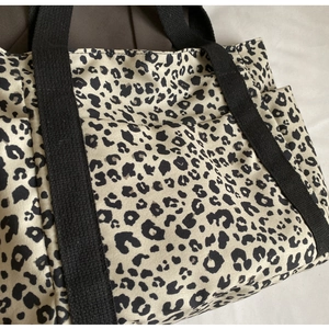 Primer plano del bolso tote de lona con estampado de leopardo y asas negras reforzadas