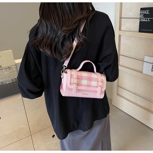 Detail of pink plaid flap bag with leather straps and elegant brand logo engraving