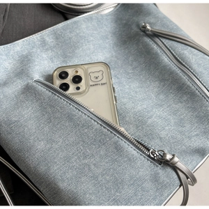 Detail of light blue denim texture tote with silver zipper and long leather puller