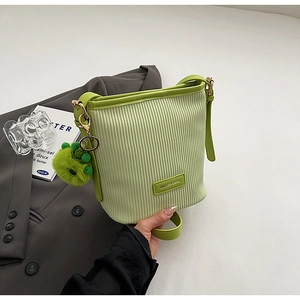 Detail of light green pleated bucket bag with plush charm and adjustable shoulder strap