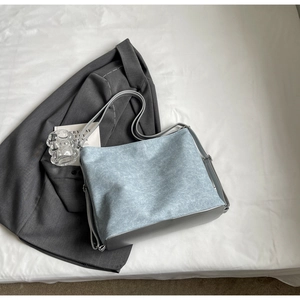 Close-up of light blue denim texture tote bag on a grey suit with daily accessories