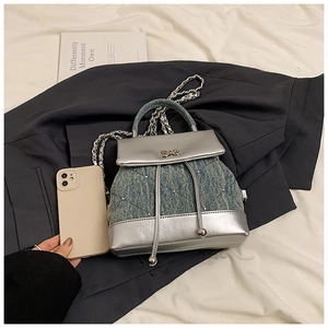 Détails d'un mini sac à dos en denim avec cuir argenté, rivets et nœud métallique élégant