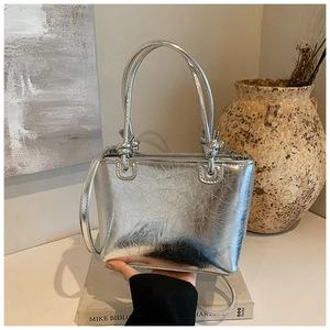Detail of silver bucket bag showing metallic wrinkled texture and knot handle design