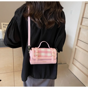 Detail of pink plaid pattern textured flap and metallic hardware on the crossbody bag