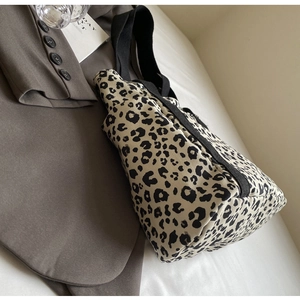 Detalle de bolso tote de lona con estampado de leopardo y correa negra en chaqueta