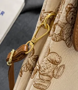 Dettaglio del gancio in metallo dorato e tracolla in pelle marrone della borsa orsetto